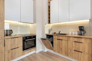 Een moderne keuken met houten kastjes, een vaatwasser, een oven en een koffiezetapparaat.