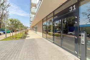 Een modern gebouw met een glazen gevel, huisnummer 31, en een keypad-deur.