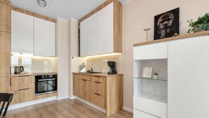 Een moderne keuken met houten kastjes, een inbouwoven en een wit aanrecht.