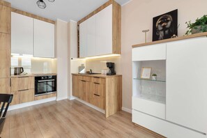 Een moderne keuken met houten kastjes, een inbouwoven en een wit aanrecht.