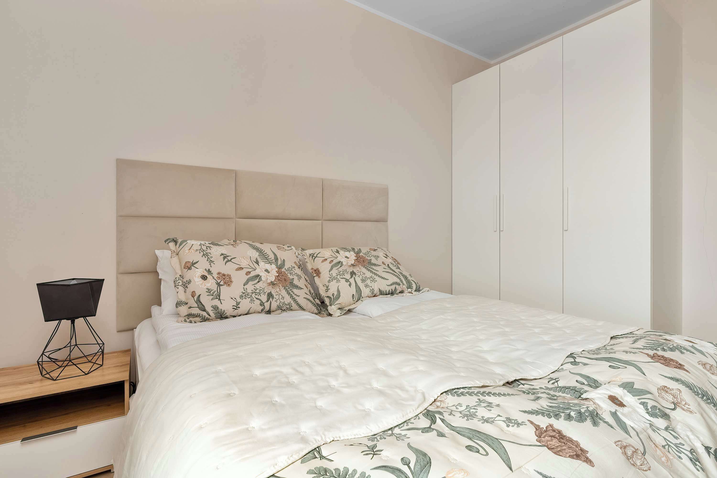 Une chambre à coucher comprenant un lit, une table de chevet, une commode et un meuble fixé au mur.