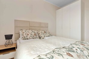 Une chambre à coucher comprenant un lit, une table de chevet, une commode et un meuble fixé au mur.