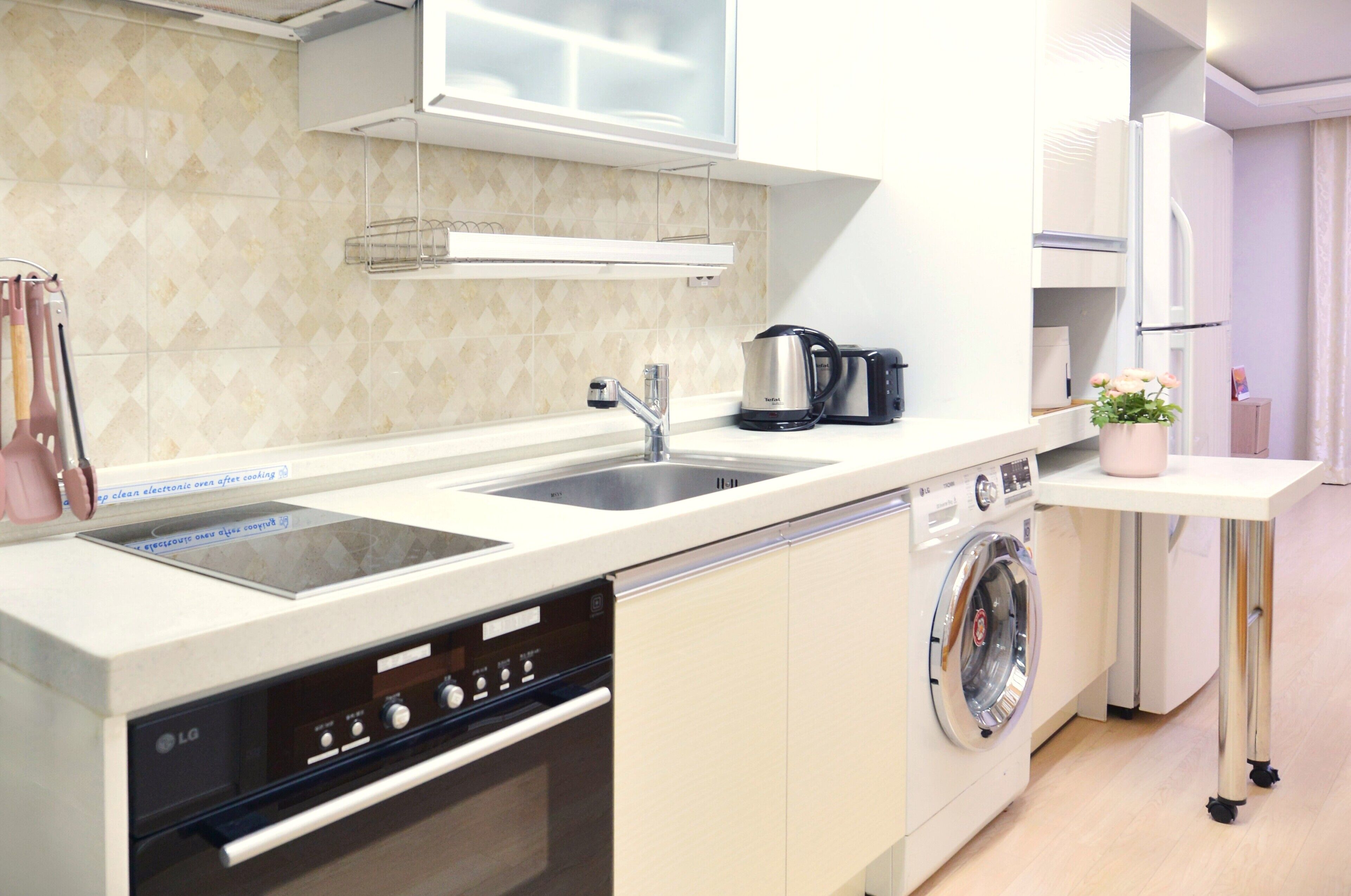 A modern kitchen with a dishwasher, washing machine, and a coffee maker.