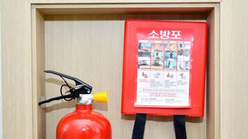 Una señal de punto de emergencia enmarco, un extintor rojo y una bolsa roja de botiquín de primeros auxilios.