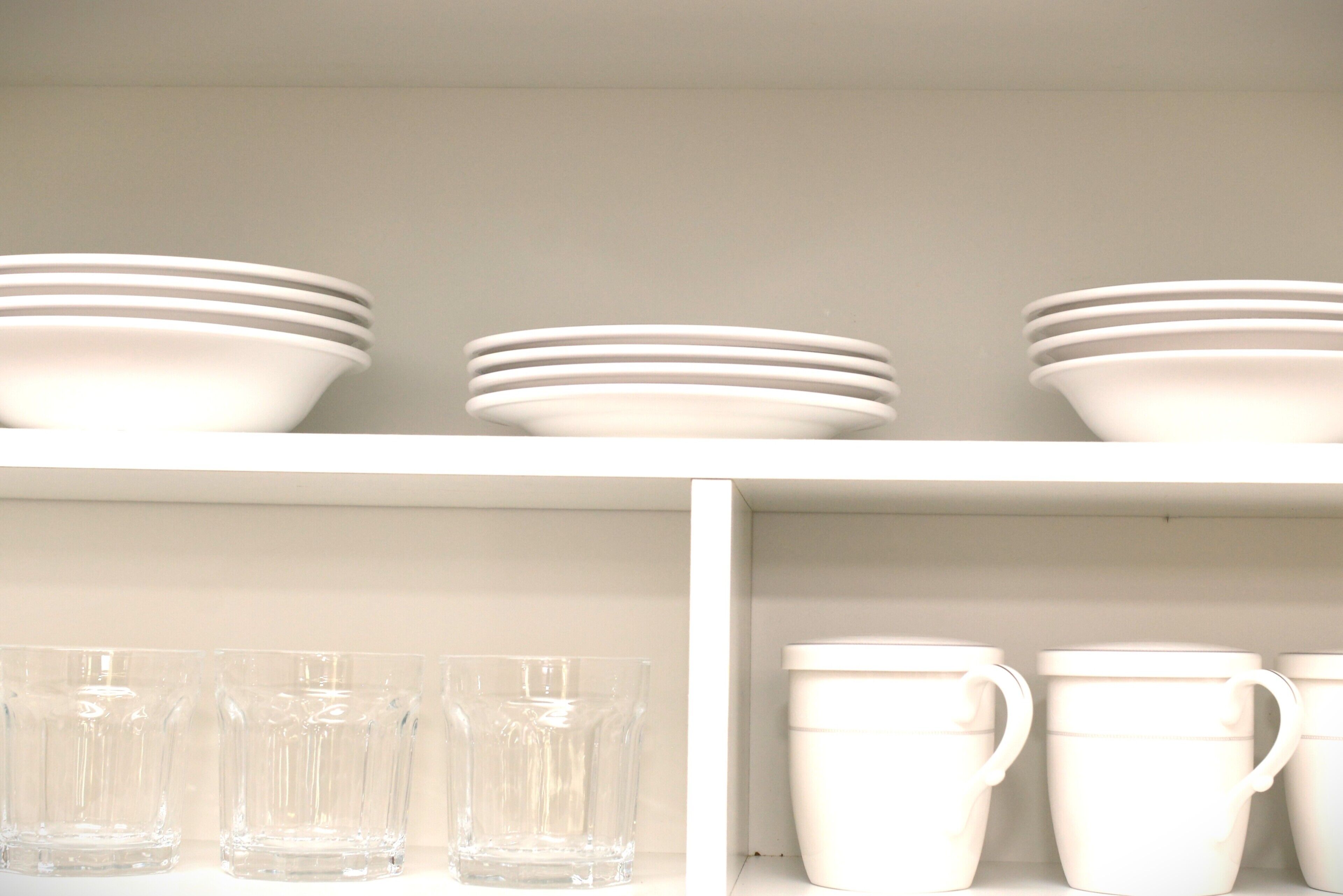A shelf with stacked white bowls and cups.