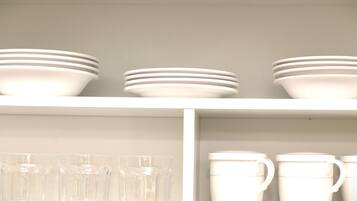A shelf with stacked white bowls and cups.
