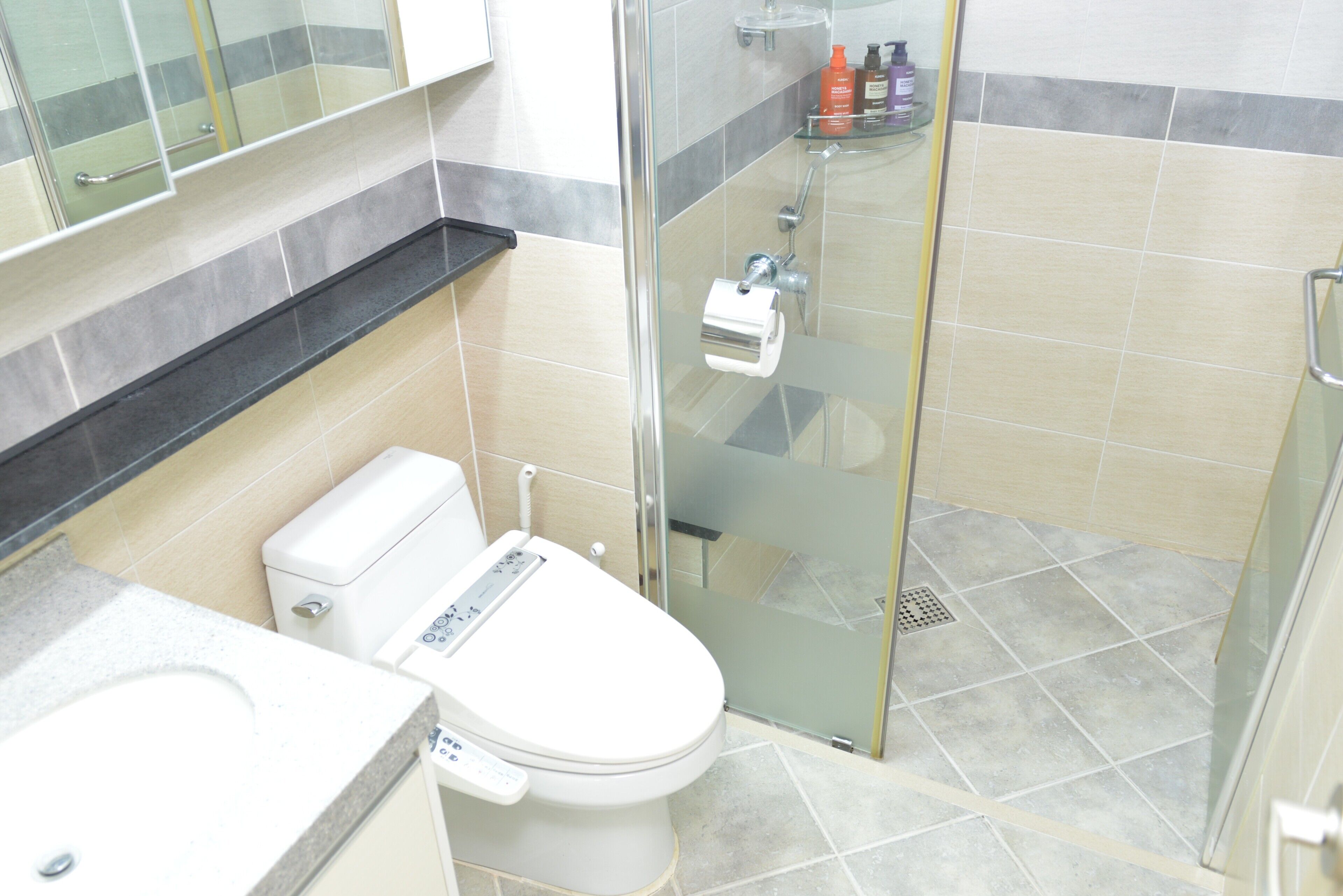 Un baño con inodoro, cabina de ducha de vidrio y lavabo.
