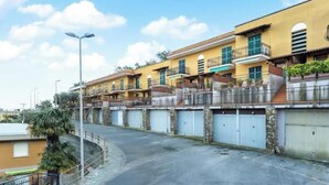A row of yellow buildings with balconies, a curved road, and a streetlight. - Hostdomus - Olive Grove House (Laigueglia)