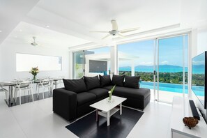 Ein modernes Wohnzimmer mit einer schwarzen Couch, einem weißen Couchtisch und einem großen Fernseher.