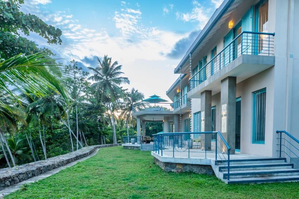 Um hotel moderno com área externa coberta, piscina e vegetação exuberante.
