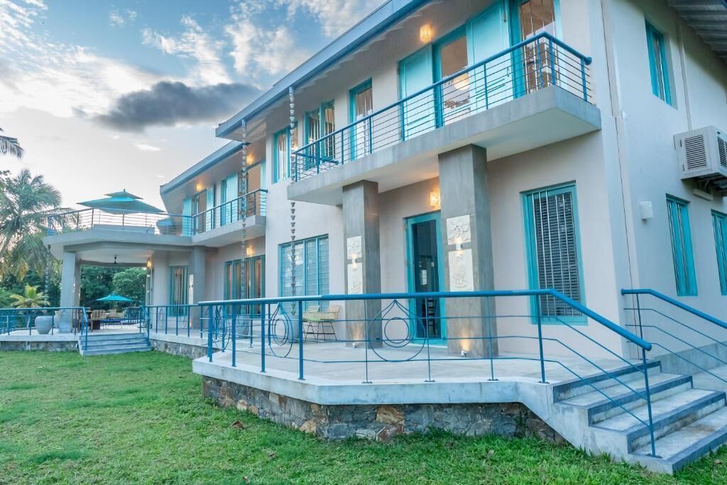 Un immeuble à plusieurs étages doté de balcons, d’un espace extérieur couvert aménagé en coin salon et d’un escalier menant à l’entrée.