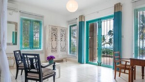 Una habitación amplia con zona de comedor, un gran ventanal con vistas y una puerta con un panel decorativo.