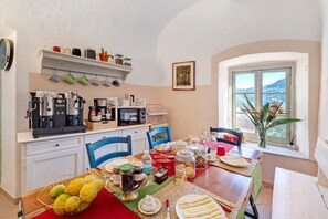 A kitchen with a dining table set for a meal, a coffee machine, and a window with a view.