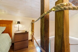 A bedroom with a wooden bed, a bedside table with a lamp, and a rope tied to a wooden post. - Room 'Arancio' with Shared Terrace, Wi-Fi and Air Conditioning (Finale Ligure)