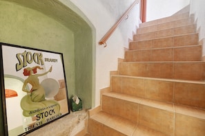 A staircase with beige tiles and a handrail, a green wall, and a poster advertising a product. - Room 'Azzurra' with Shared Terrace, Wi-Fi and Air Conditioning (Finale Ligure)