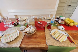 A dining table set with plates, cutlery, and various food items. - Room 'Azzurra' with Shared Terrace, Wi-Fi and Air Conditioning (Finale Ligure)