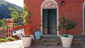 Un edificio con facciata rossa, porta verde e un arco decorativo bianco.
