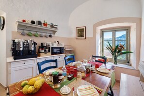 Una cucina con un tavolo da pranzo apparecchiato, una macchina da caffè e una finestra con vista.