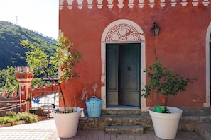 Un edificio con facciata rossa, porta verde e un arco decorativo bianco.