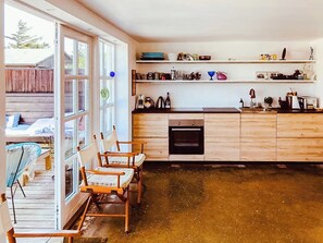 A kitchen with wooden cabinets, a built-in oven, and a window overlooking a deck. - In Cold Hawaii with beach in backyard (Thisted)