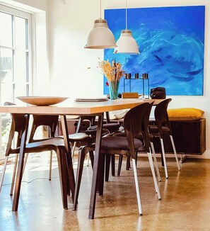 A dining area with a table, chairs, pendant lights, and a large abstract painting on the wall. - In Cold Hawaii with beach in backyard (Thisted)
