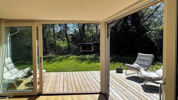 A deck with wooden flooring, two white lounge chairs, and a small table. - Summer house near bathing jetty at Fynshoved (Martofte)