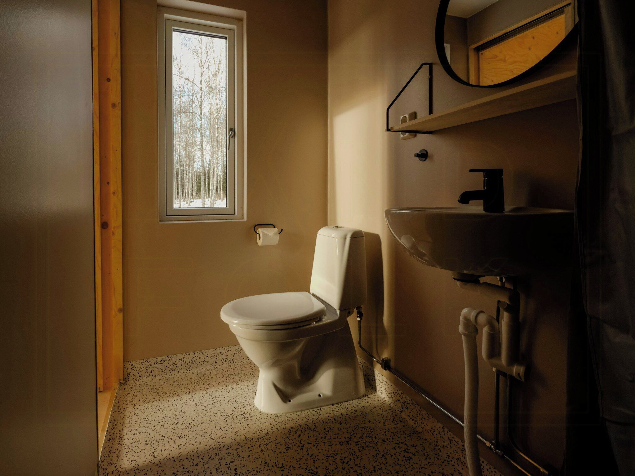 Une petite salle de bain avec des toilettes, un lavabo et une fenêtre.