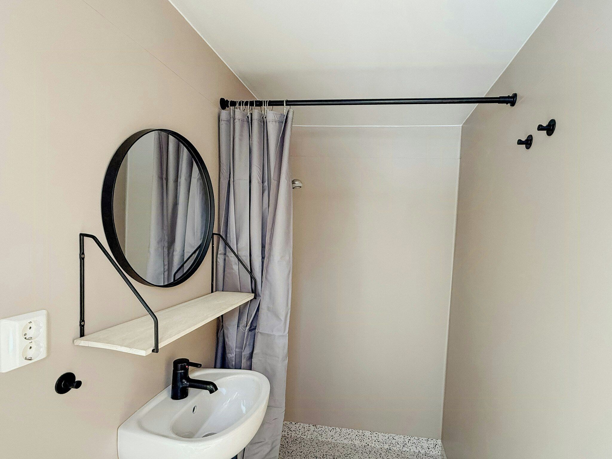 Casa de banho com lavatório branco, espelho, porta-toalhas e cortina de chuveiro.