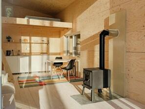 Eine moderne Küche mit Holzwänden, einem Essbereich mit Stühlen, einem Herd und einem Fenster.