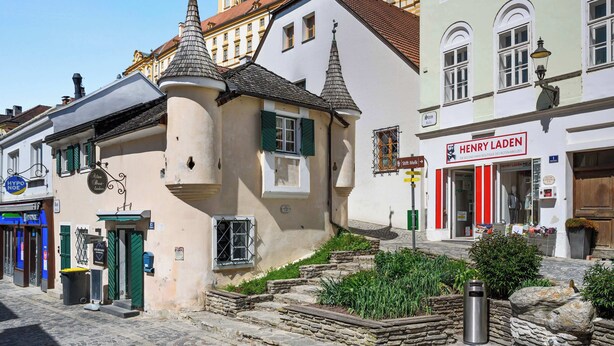 A street with historic buildings, a boutique hotel named 'Henry Laden,' and a small garden area.