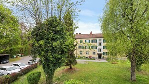A residential building with a green lawn, parked cars, and trees.