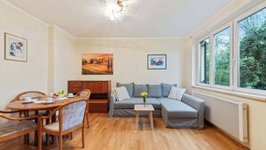 A cozy living room with a dining table, sofa, and artwork on the walls.