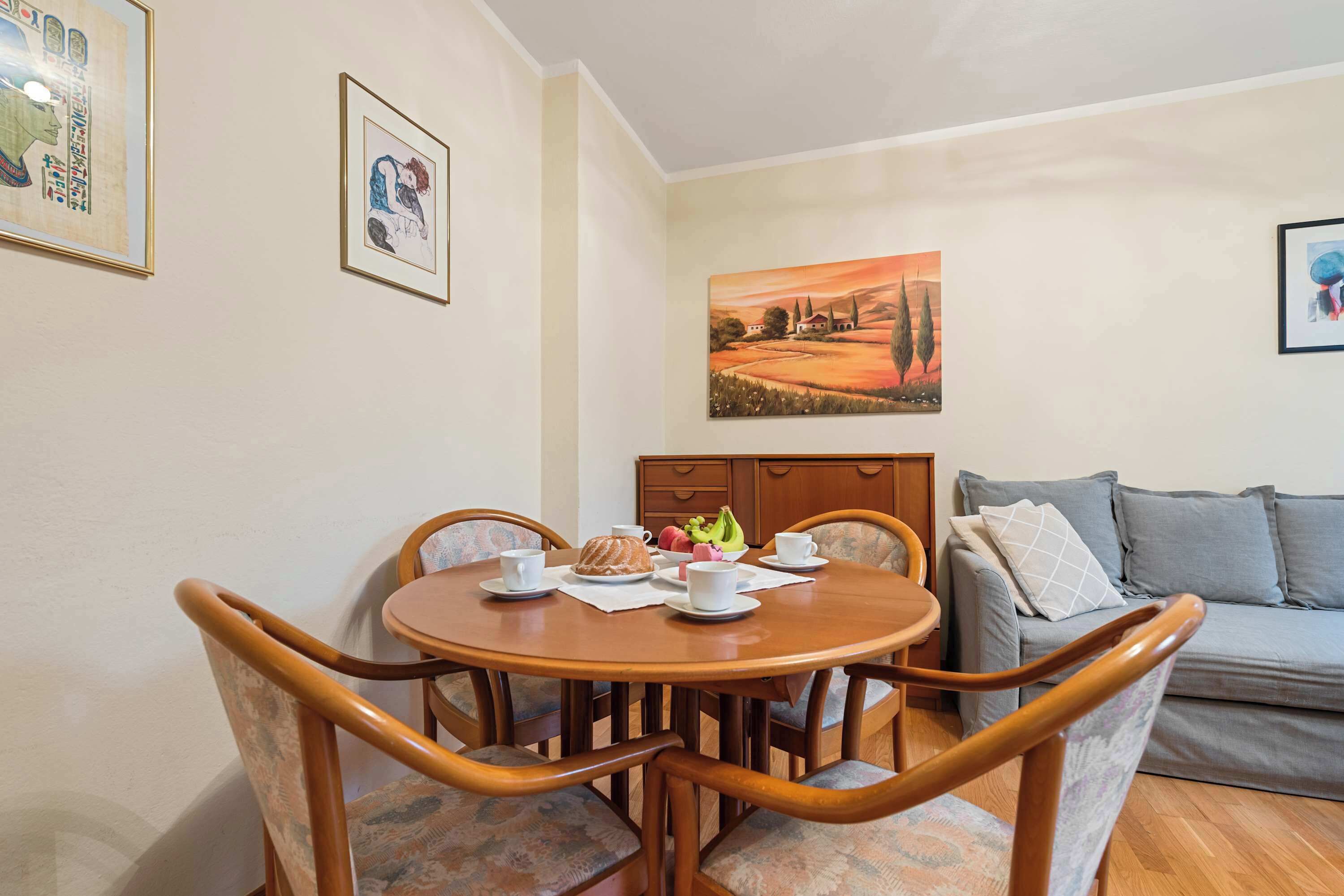 A dining area with a round table, chairs, and a sofa.