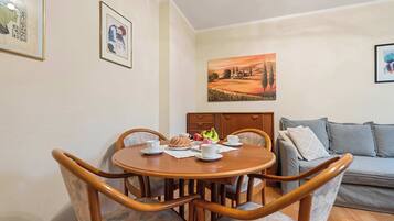 A dining area with a round table, chairs, and a sofa.