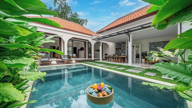 A modern pool area with a floating basket of snacks, surrounded by lush greenery and a clear blue sky. - Alisa 4 Villa (Kerobokan)