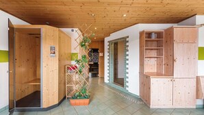 Interior de madera con techo de madera, una planta en canasta y zona de ducha.