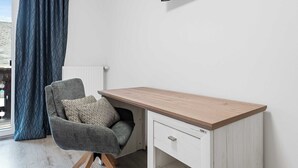A room with a desk, chair, and a TV mounted on the wall.