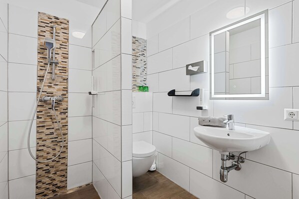A modern bathroom with a shower, toilet, and sink.
