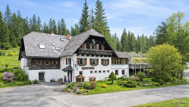 A two-story building with a sloped roof, a balcony, and a small porch area.