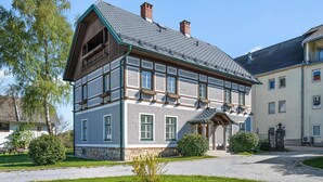 Ein traditionelles, zweistöckiges Gebäude mit einer Steinaußenwand, zahlreichen Fenstern und einem markanten Giebeldach.
