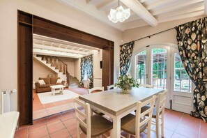 A dining area with a table and chairs, a staircase, a sofa, and a view through a door. - Stone farmhouse in the Chianti hills (Montaione)