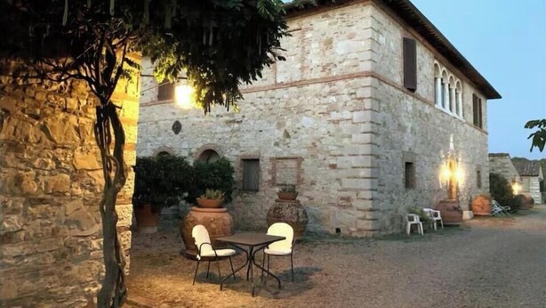 A stone building with a courtyard, outdoor seating, and potted plants. - Panoramic guesthouse in the Siena hills (Castelnuovo Berardenga)