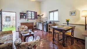 A spacious living area with a dining table, chairs, a sofa, and a kitchen area with a window. - Panoramic guesthouse in the Siena hills (Castelnuovo Berardenga)