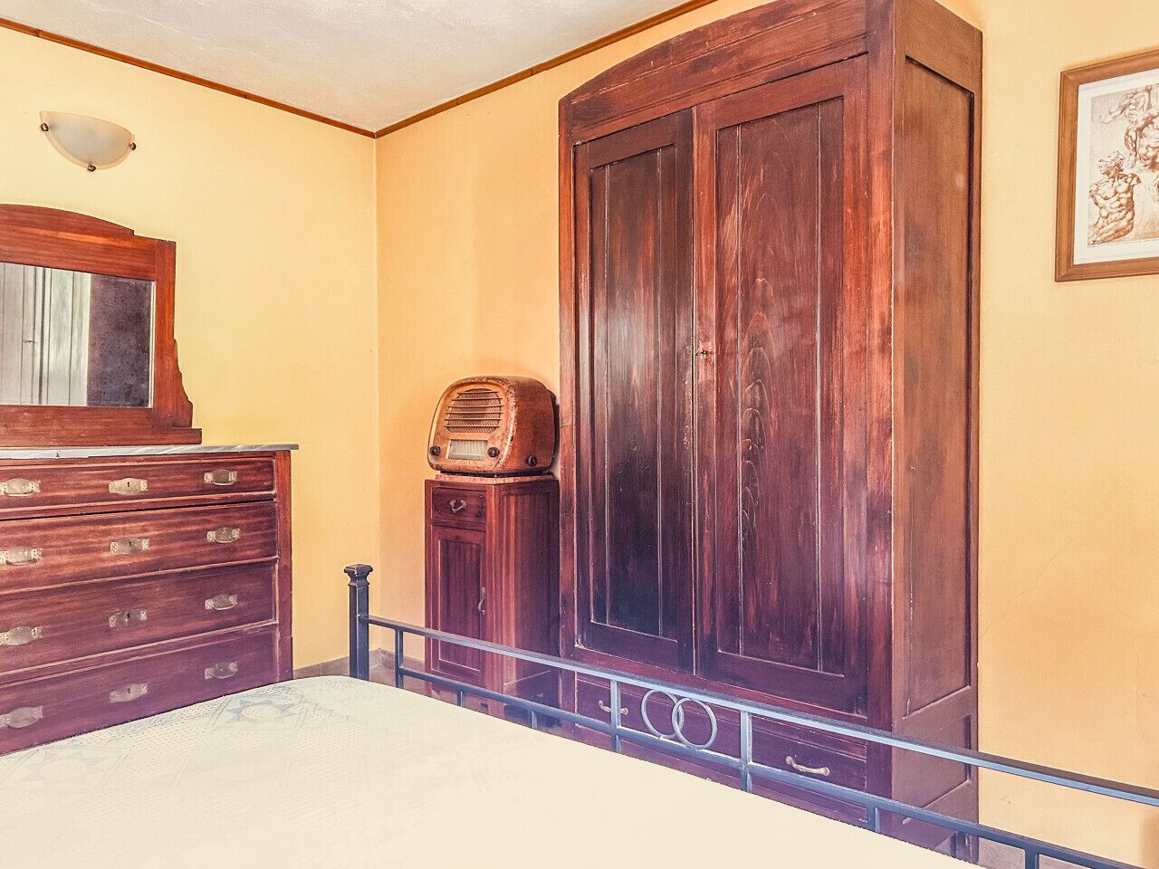 Een kamer met een grote houten garderobe, een vintage radio en een dressoir met meerdere lades.