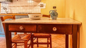 Une cuisine avec une table en bois, deux chaises, un bol et un vase à motifs posé sur le comptoir.