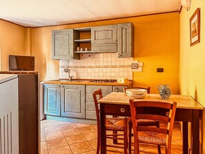 A compact kitchen with a dining table, chairs, a stove, and cabinets.