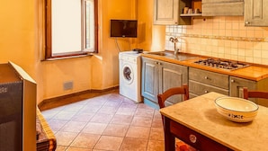Une cuisine compacte équipée d’un lave-linge, d’une cuisinière et d’un coin repas avec une table et des chaises.