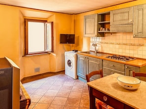 A compact kitchen with a washing machine, a stove, and a dining area with a table and chairs.