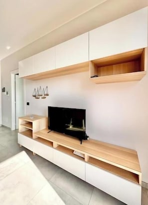 En moderne stue med indbygget tv, træhylder og et minimalistisk design.