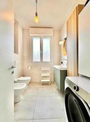 Et lille, moderne badeværelse med toilet, bidet og vaskemaskine.